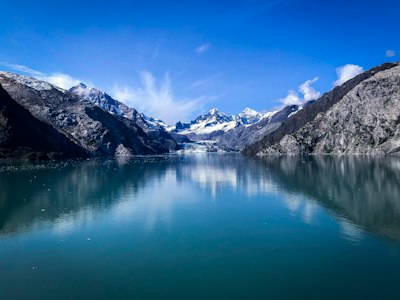 lake near snow covered mountain under blue sky during daytime