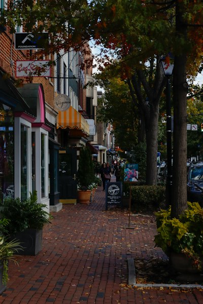 a brick sidewalk with shops and people walking on it