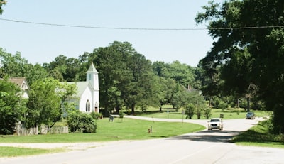 White church, green trees, and winding road with a car