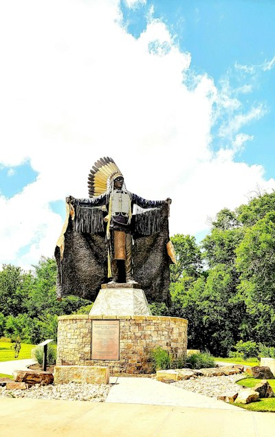 a statue of a native american standing on a rock
