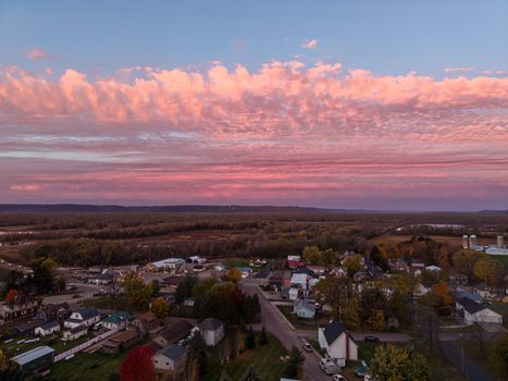 Aerial view of Nelson, Wisconsin showcasing a picturesque sunset with vibrant clouds over a serene village landscape.