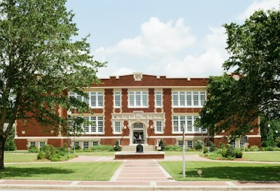 Old brick school building framed by trees