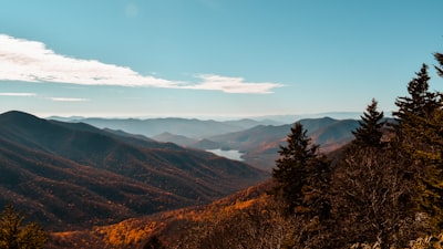 a scenic view of a mountain range with trees in the foreground