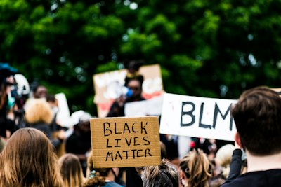 people holding white and blue wooden signage during daytime