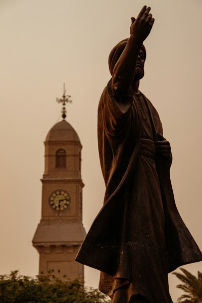 A statue in front of a clock tower