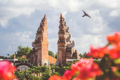 The split gate of a Balinese temple in Bali, Indonesia, with blurred flowers