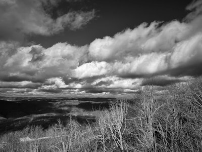 a black and white photo of clouds over a valley