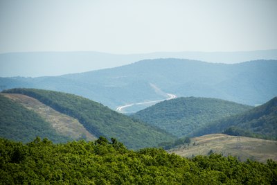 A winding highway through rolling green hills under a hazy blue sky