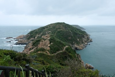Green island with winding path and rocky coastline