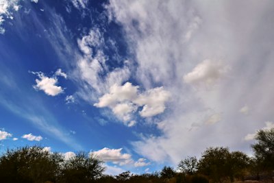 a blue sky with white clouds and some trees
