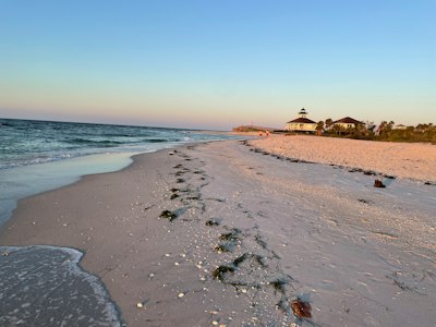 a sandy beach with a light house in the distance