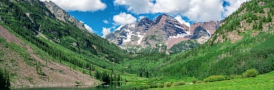 green trees and mountain under blue sky and white clouds during daytime