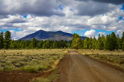 A dirt road leads to a mountain beneath clouds