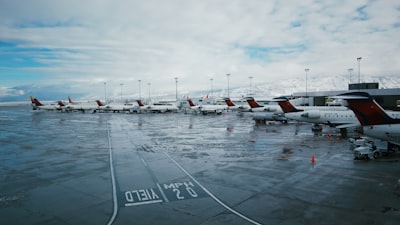 white airplanes on railway under white and blue sky