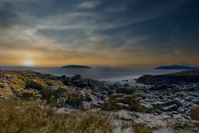 a rocky beach with a body of water in the background