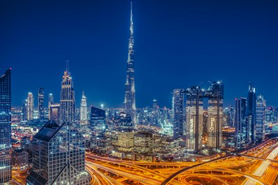 The Burj Khalifa towering over the illuminated Dubai skyline at night with busy highways