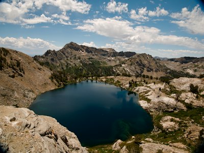 Deep blue mountain lake surrounded by rocky terrain and trees