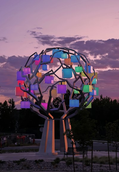 A tree sculpture with colorful glowing lights at twilight