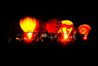 Hot air balloons glow brightly at night