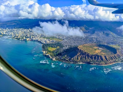 aerial view of green and brown island under blue sky and white clouds during daytime