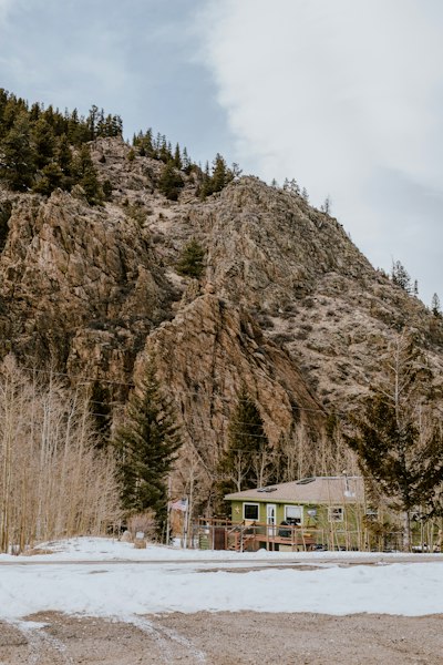 a house in front of a mountain with snow on the ground
