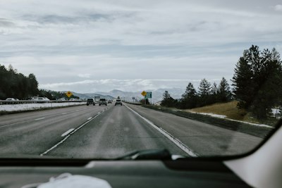 a car driving down a highway next to a forest