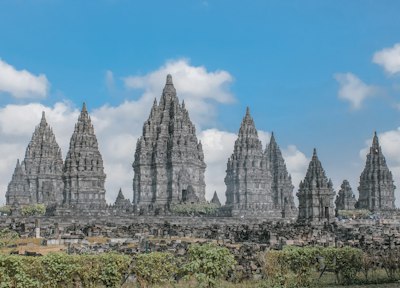 The stone spires of Prambanan temple complex under a bright blue sky