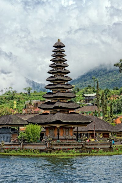 A multi-tiered thatched roof temple on the shore of a lake in Bali