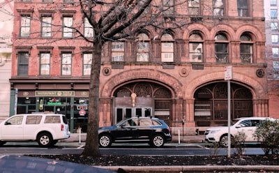 blue sedan parked beside brown concrete building during daytime