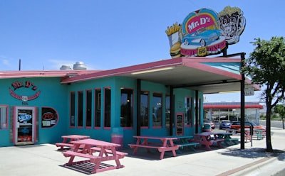 A blue and pink building with a pink picnic table outside of it