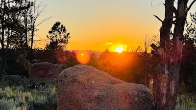 the sun is setting over a rocky outcropping