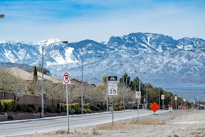 Snow-capped mountains overlook a suburban street with signs