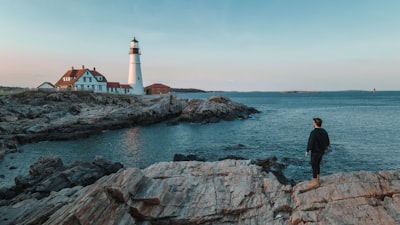 a man standing on a rock next to a lighthouse