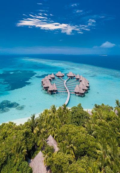 Overwater bungalows arranged in a circle on a turquoise lagoon in the Maldives