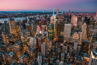 An aerial view of the Manhattan skyline at night with glowing office buildings