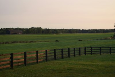 a field with a fence and a barn in the distance