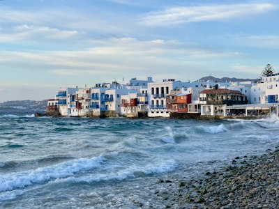 a row of houses sitting on top of a beach next to the ocean