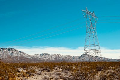 gray electric tower on brown grass field during daytime