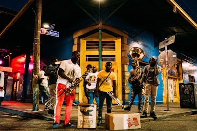 people holding musical instruments while standing on street during nighttime