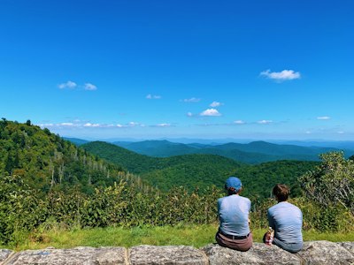 a couple of people sitting on top of a stone wall