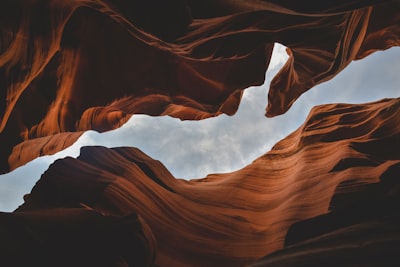 A view of the cloudy sky through the orange sandstone walls of Antelope Canyon