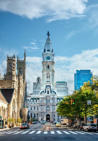Philadelphia City Hall tower rising above a street with cars and a crosswalk