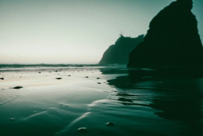 Ocean waves wash over the beach near large rocks