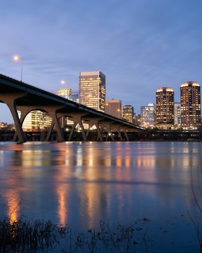 bridge over water near city buildings during night time
