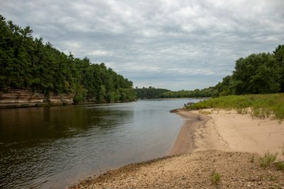 a river with a beach and trees