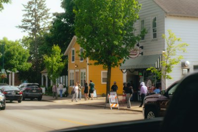 People stroll past a yellow building on a sunny street