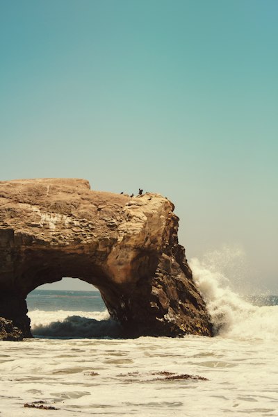 person standing on rock formation in sea during daytime