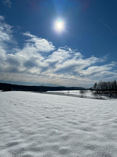 the sun is shining over a snowy field