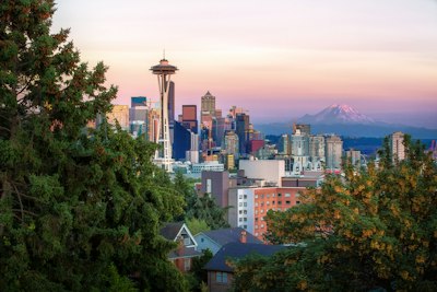 The Space Needle and Seattle skyline with Mount Rainier under a warm sky