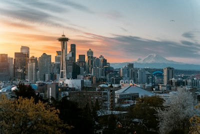 The Space Needle and Seattle skyline with Mount Rainier under a warm orange sky